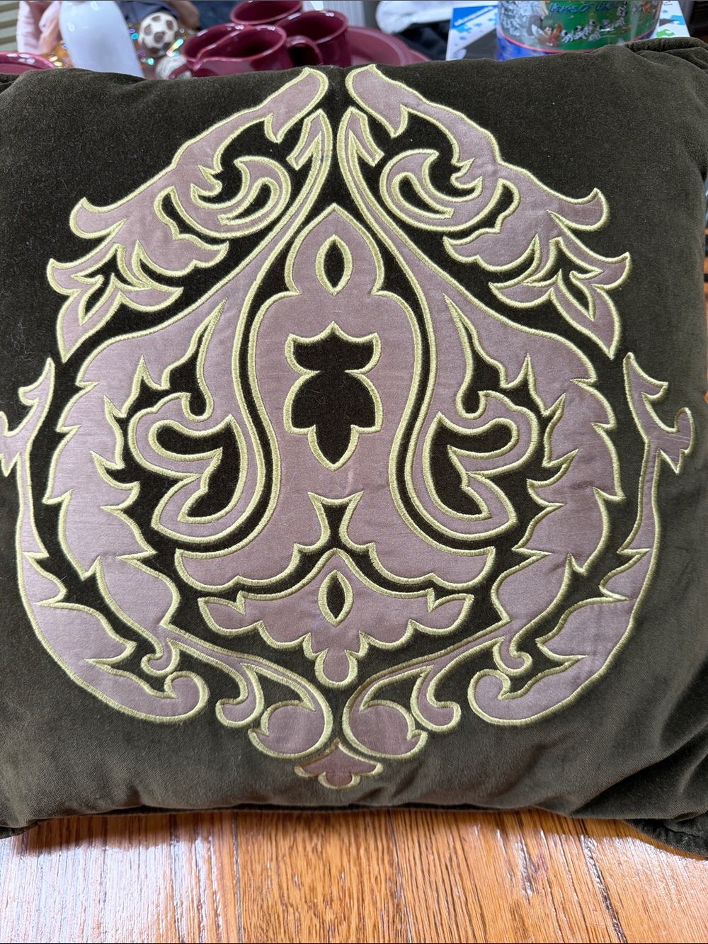 Reba green velour pillow with embroidered scroll design on front.